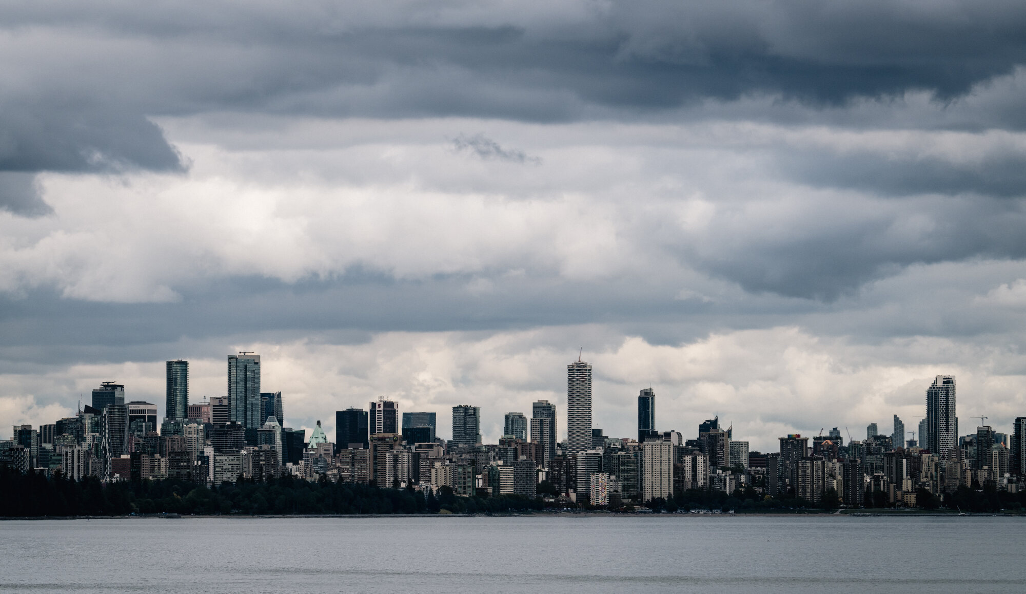 Vancouver skyline stretching across the water beneath a dramatic layered storm sky