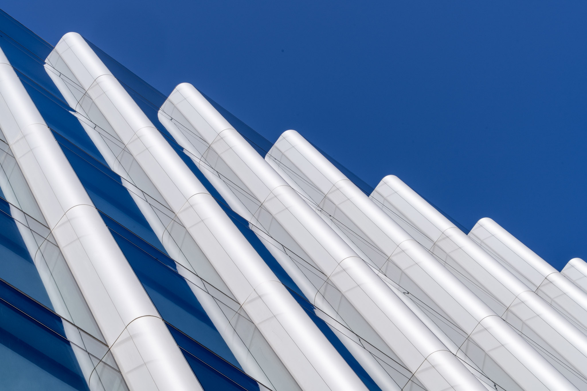 White twisting aluminium fins crossing reflective blue glass on the Monument Building in London